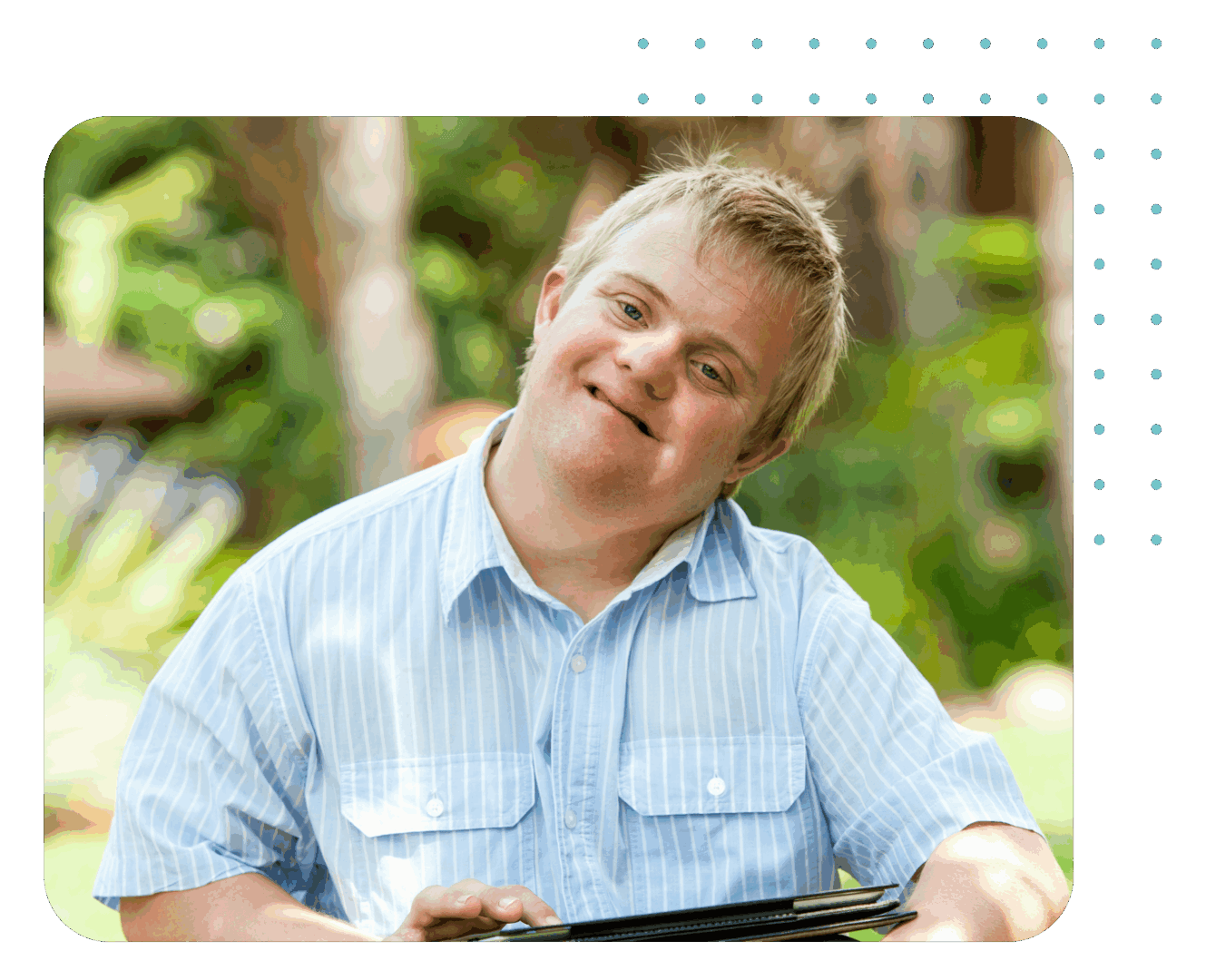 Man smiling outdoors, holding a tablet.