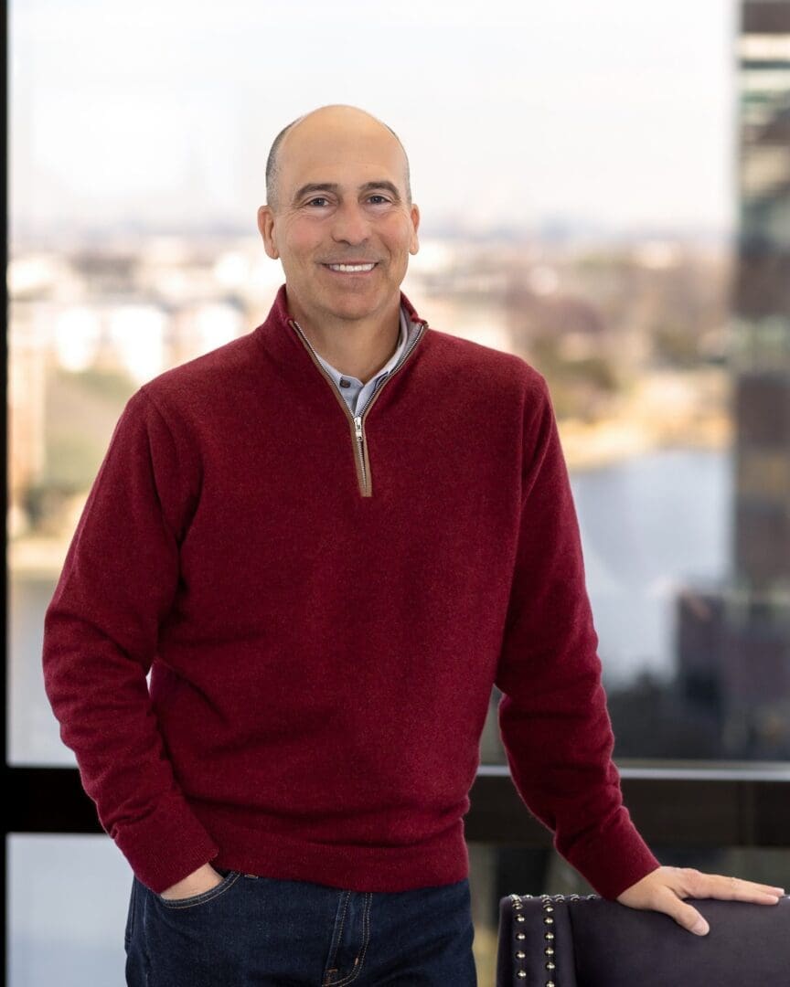 A man in a red sweater standing with his hands on his hips.