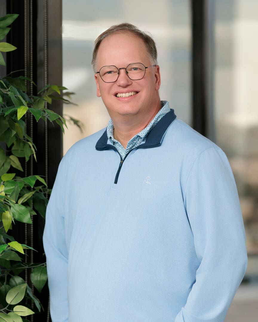 Man in light blue sweater, smiling indoors.